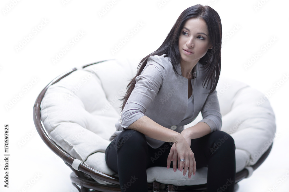 Fototapeta premium Young woman sitting in a round cozy soft big chair.