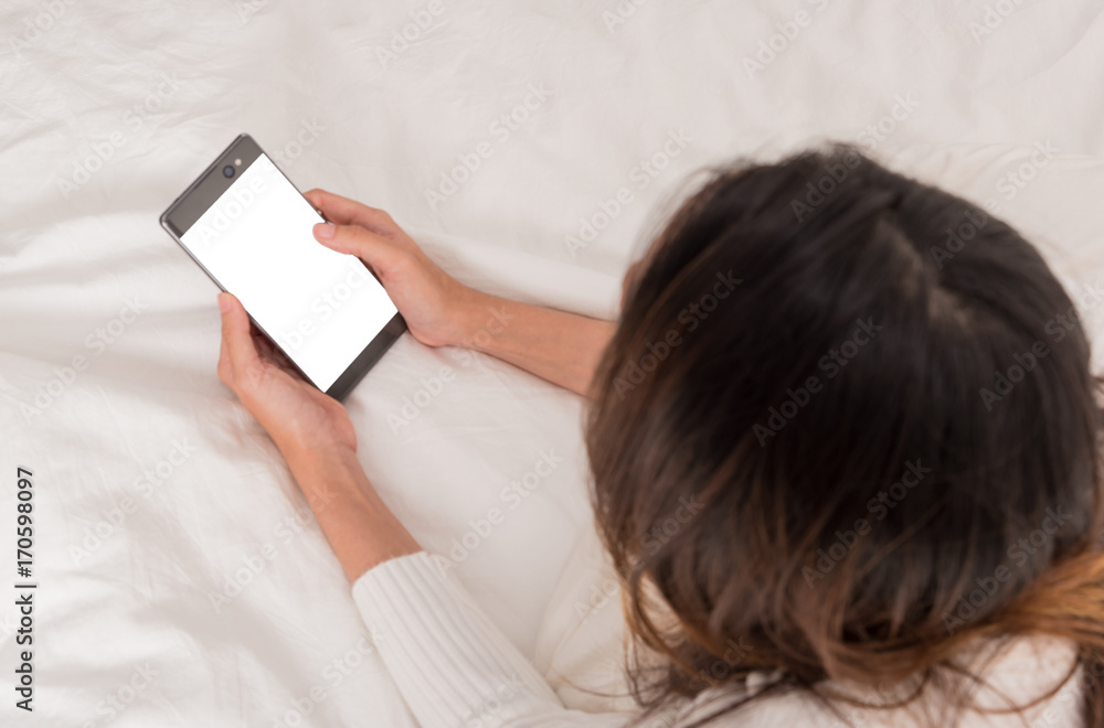 Top view ,woman on bed technology, communication and people lifestyle concept - happy young woman lying in bed and texting on smartphone at home bedroom,copy space Top view ,woman on bed technology, communication and people lifestyle concept - happy young woman lying in bed and texting on smartphone at home bedroom,copy space