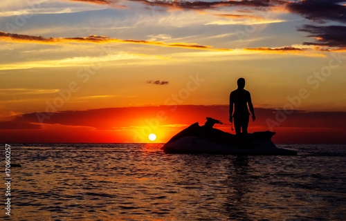 silhouette of a man on a jet ski in the sun