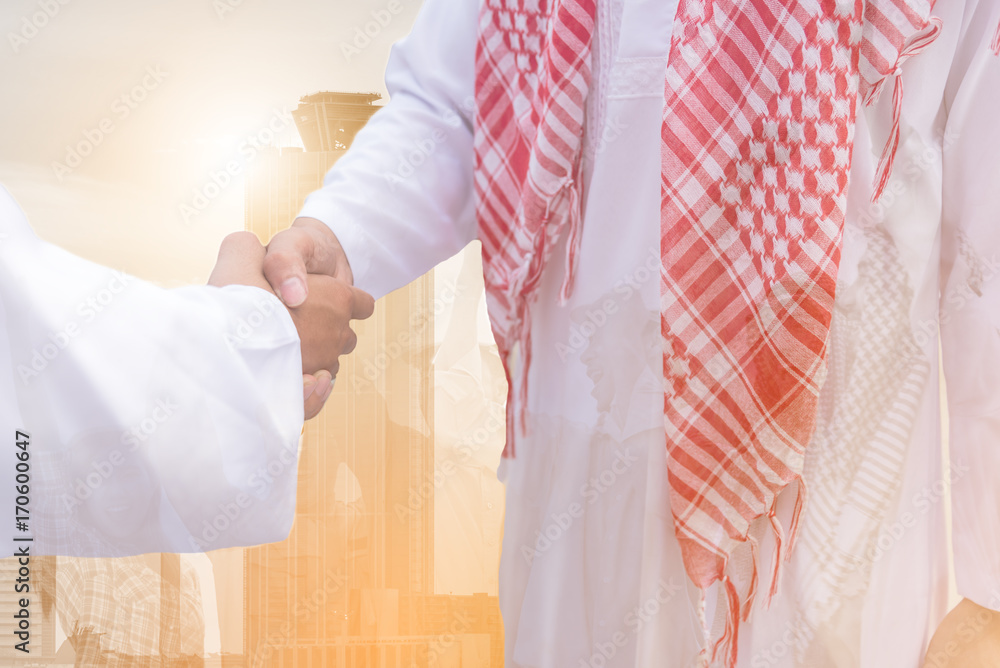 Double exposure of Arabian Business partnership meeting concept.photo businessman handshake. Successful businessmen handshaking after perfect deal.close up Double exposure of Arabian Business partnership meeting concept.photo businessman handshake. Successful businessmen handshaking after perfect deal.close up