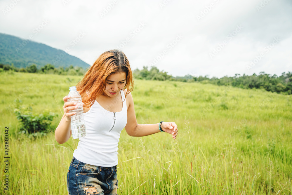 Asian women travel relax in the holiday. Drink Water on a green pasture. Asian women travel relax in the holiday. Drink Water on a green pasture.