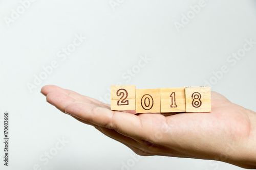 Man hold wood block with wording 2018 on concrete background (Concept for Happy new year 2018)