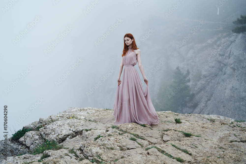 woman in a long dress against a background of fog, rock, beautiful nature woman in a long dress against a background of fog, rock, beautiful nature