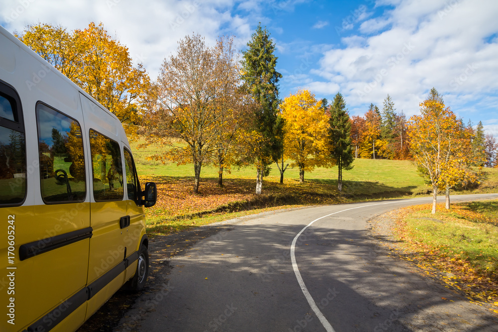 Yellow bus on the turn of autumn road outside the city