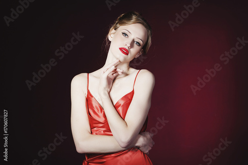 Young beautiful blond woman in red dress over red background. Fashion concept.