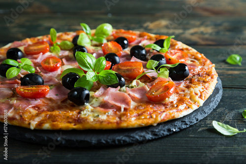 Pizza on a thin dough with olives and fresh basil