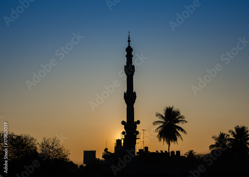 Warm tones as a bright sun sets behind the silhouette of the Friday Mosque in Old Delhi, India, on a clear day with no clouds photo