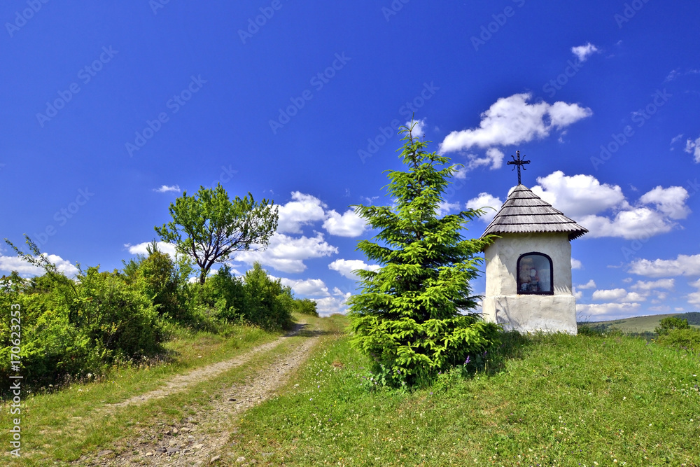 Small white chapel in green field near Jasliska, Beskid Niski, Poland