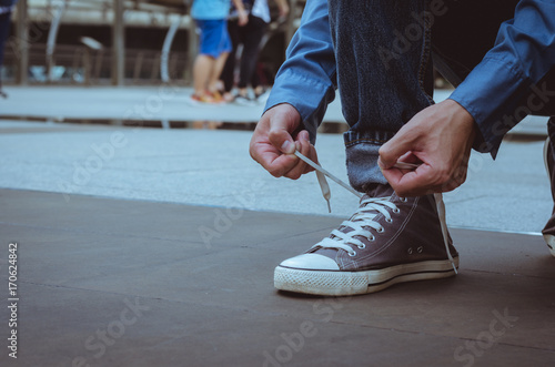 handsome man sit on concrete floor tying shoelace to wearing the shoes.