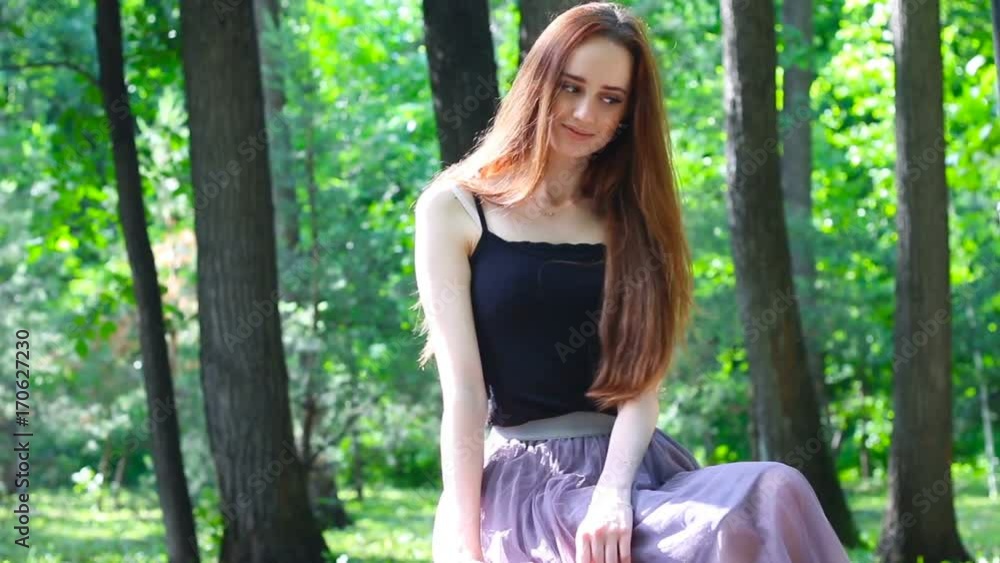 Beautiful cute girl sits in the summer park Beautiful cute girl sits in the summer park