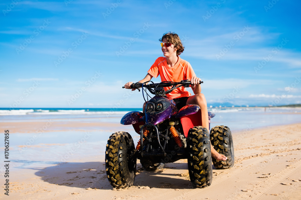 Teenager riding quad bike on beach