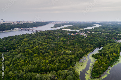 Panoramic view of Kiev city with the Dnieper River and a large green park area in the middle . Aerial view