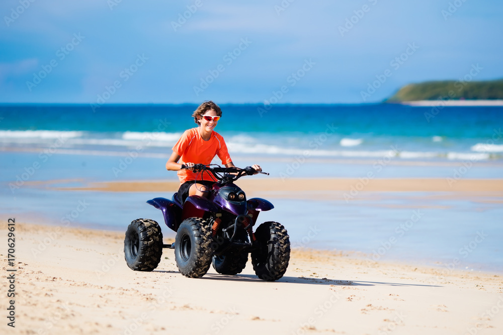 Obraz premium Teenager riding quad bike on beach