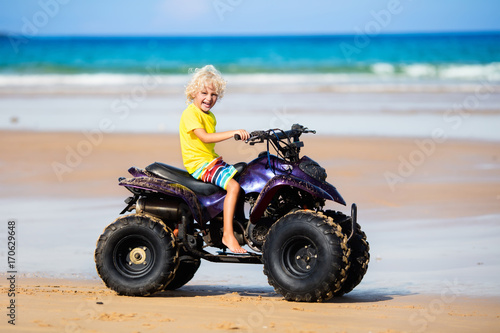 Child on quad bike at beach. All-terrain vehicle.