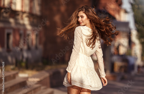 Beautiful young girl with long healthy hair, nice dress walking in the street. Lifestyle concept. Youth and happiness. photo