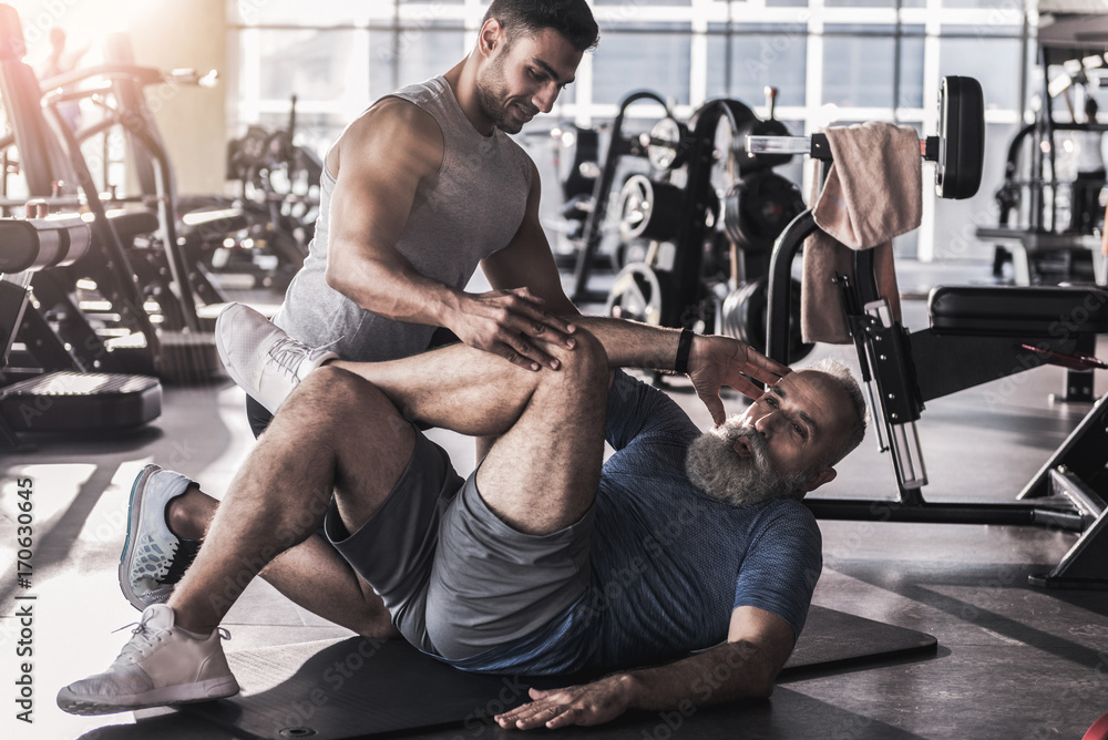 Obraz premium Senior male is enjoying sport in athletic center with trainer