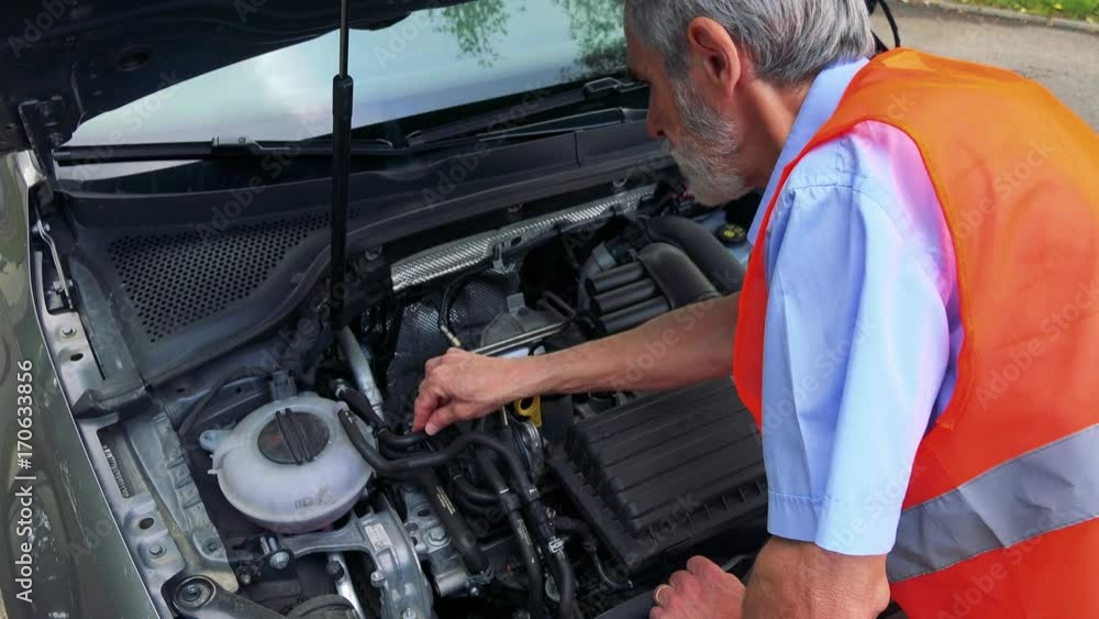 Senior man wears warning vest and controls engine of the car - closeup 