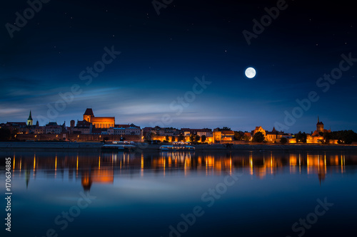 Photography Old town reflected in river at sunset. Torun, Poland.