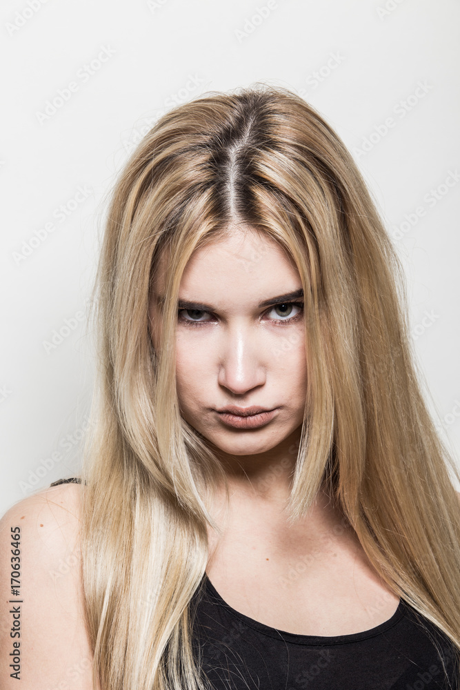 Close-up portrait of a young beautiful blonde girl on a light background. A woman with different emotions on her face. Close-up portrait of a young beautiful blonde girl on a light background. A woman with different emotions on her face.