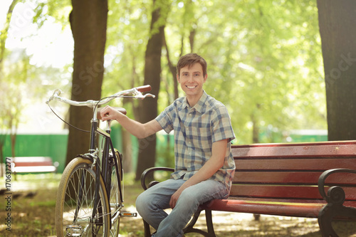 Young handsome man with bicycle outdoors on sunny day