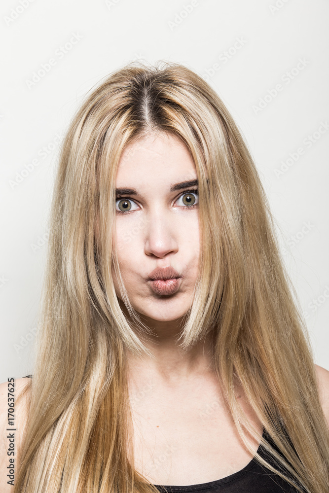 Close-up portrait of a young beautiful blonde girl on a light background. A woman with different emotions on her face. Close-up portrait of a young beautiful blonde girl on a light background. A woman with different emotions on her face.