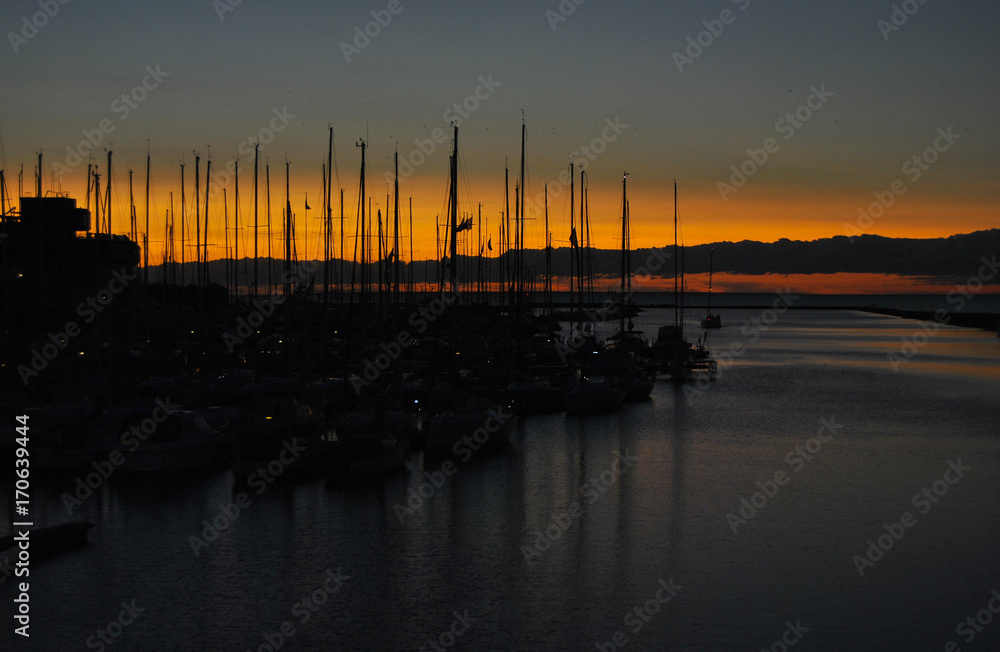 Beautiful sunset in the port. Sunset against the background of yachts. Beautiful evening sky in a yacht club. Autumn sunset, autumn sky. Romantic landscape.