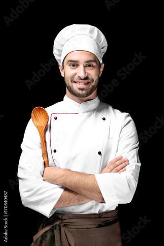 Young male chef on black background