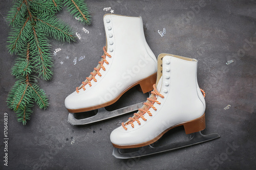 Figure skates with fir branch on grey background