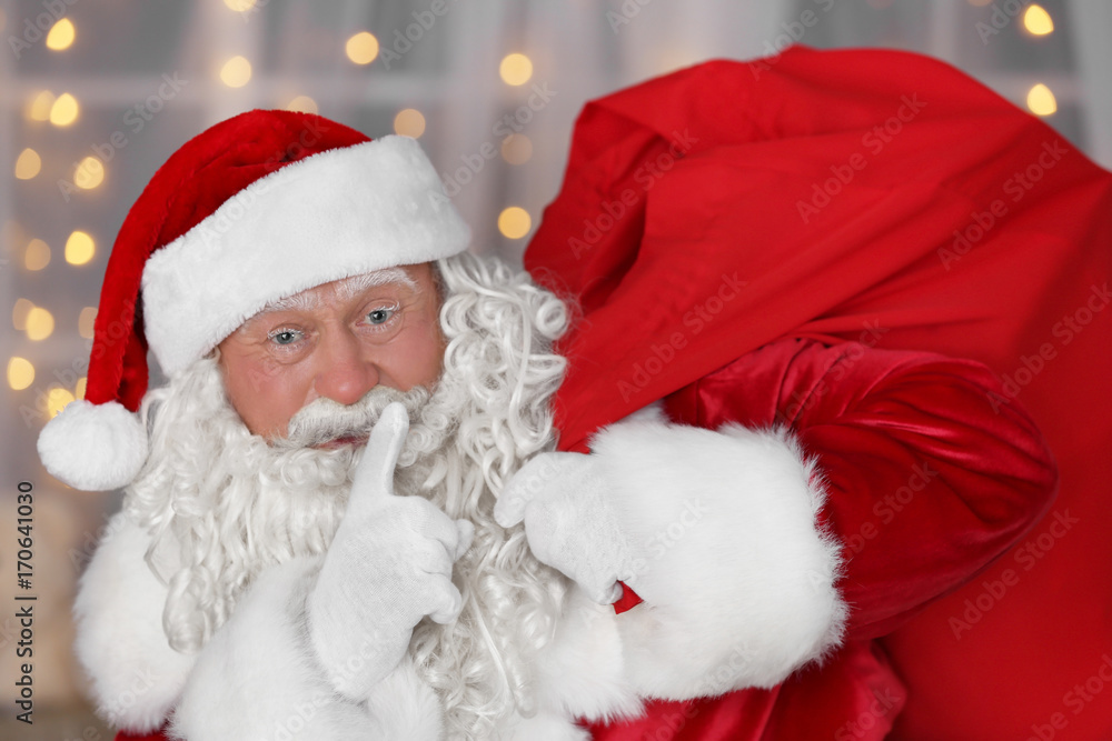 Authentic Santa Claus with big red bag full of gifts against blurred Christmas lights Authentic Santa Claus with big red bag full of gifts against blurred Christmas lights