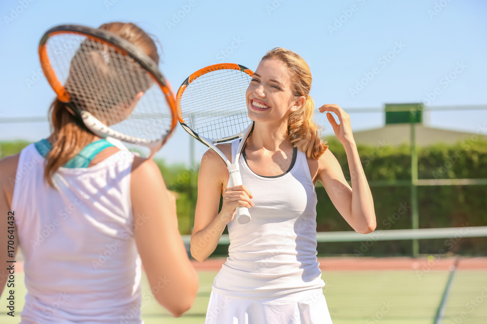 Young women playing tennis on court
