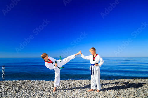 Тренировка двух детей на пляже, на море: тхэквондо, спорт