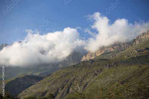 Горный пейзаж. Красивый вид на живописное ущелье, панорама горной местности, белые облака на синем небе. Природа и горы Северного Кавказа © Ivan_Gatsenko
