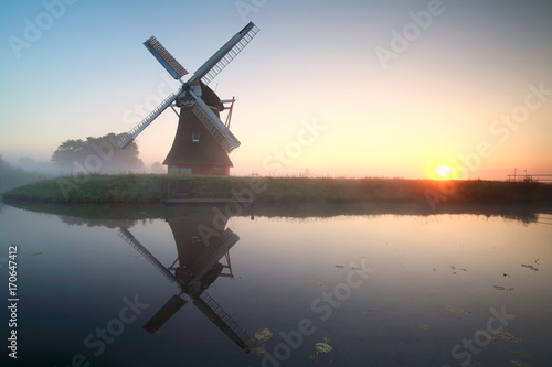 charming windmill by lake at sunrise