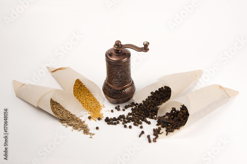 Vintage bronze mill for seasonings and various seasonings on a white background. photo