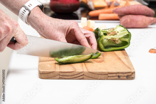 green bell pepper being chopped on a wooden chopping board
