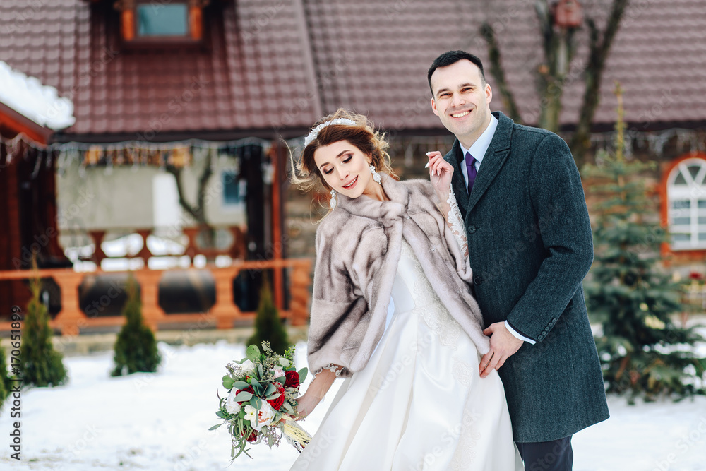 Winter wedding outdoors on background of snow-covered house. Winter wedding outdoors on background of snow-covered house.