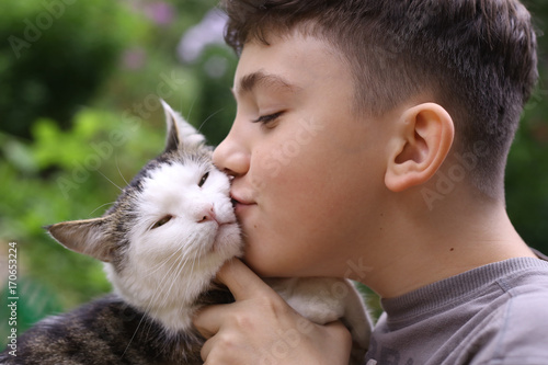 happy boy hold cat smiling close up photo on the summer green garded background photo