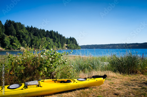 Yellow kayak on a grassy beach next to the water. Location: Vashon Island near Seattle