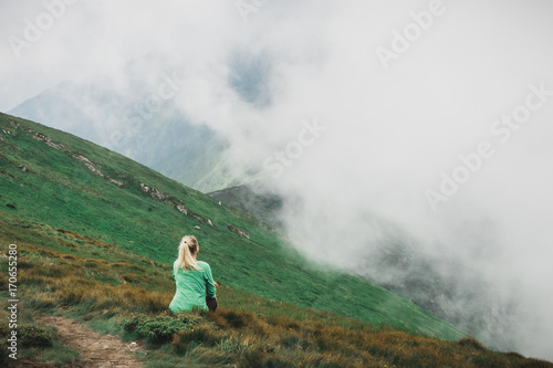 Fototapeta Naklejka Na Ścianę i Meble -  Landscape, travel, tourism. Girl-tourist in the mountains, shrouded in fog. Horizontal frame