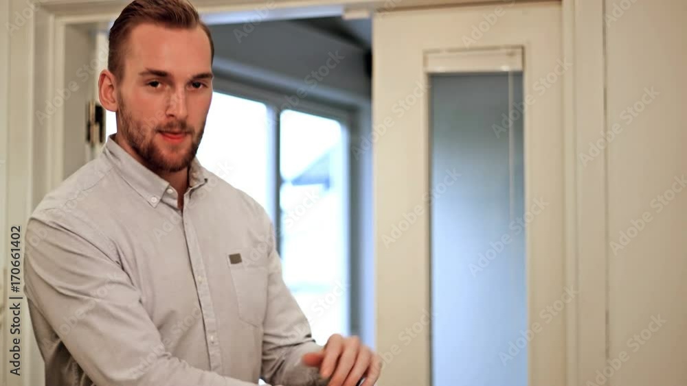 Attractive man wearing a blue shirt walking indoors hallway, stopping and looking at camera with arms crossed and smiling. Attractive man wearing a blue shirt walking indoors hallway, stopping and looking at camera with arms crossed and smiling.
