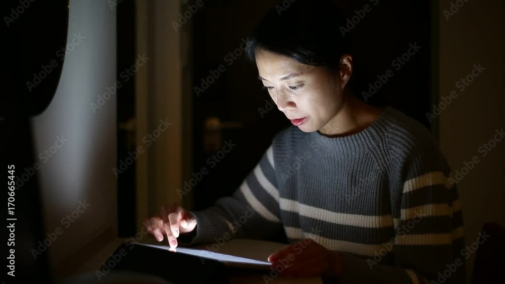 Woman using tablet computer at home in the night time Woman using tablet computer at home in the night time
