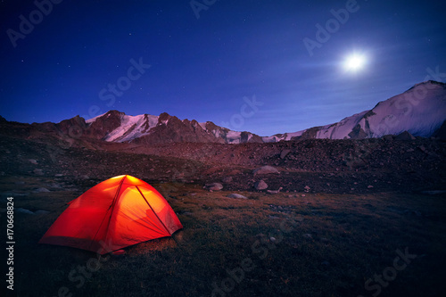 Orange tent glows under night sky