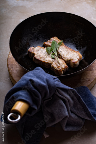 Two pork loin chops cooking in a wok with sage. photo