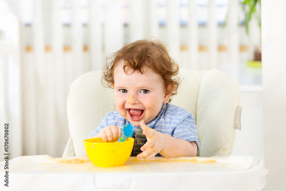 Cute baby boy eating by himself on high chair Cute baby boy eating by himself on high chair