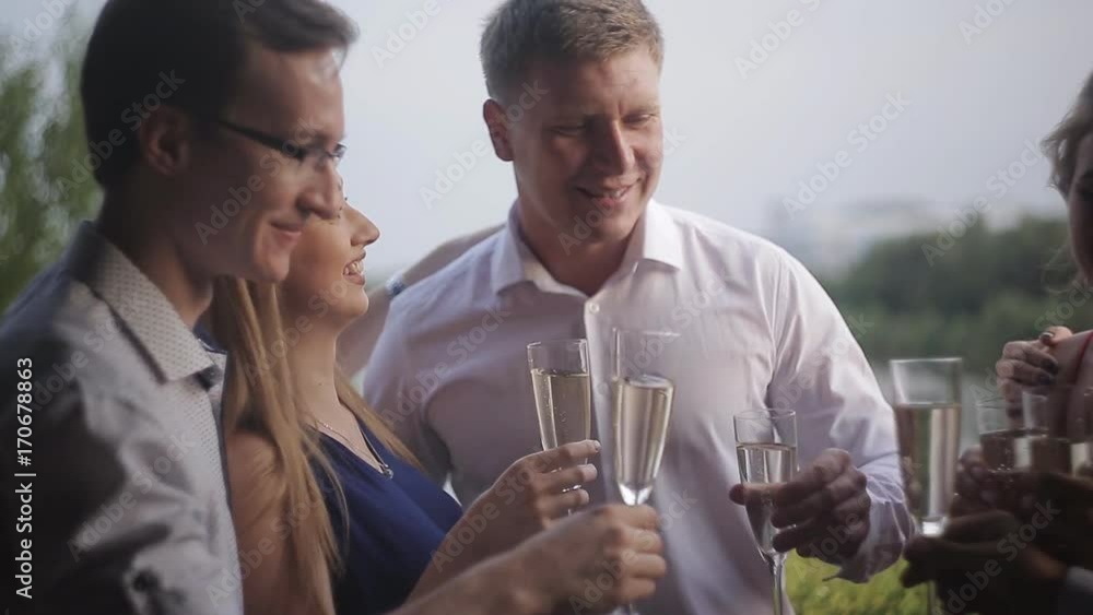 In the summer cafe, friends congratulate a young couple with an engagement. A group of friends hug a young couple in a summer restaurant In the summer cafe, friends congratulate a young couple with an engagement. A group of friends hug a young couple in a summer restaurant