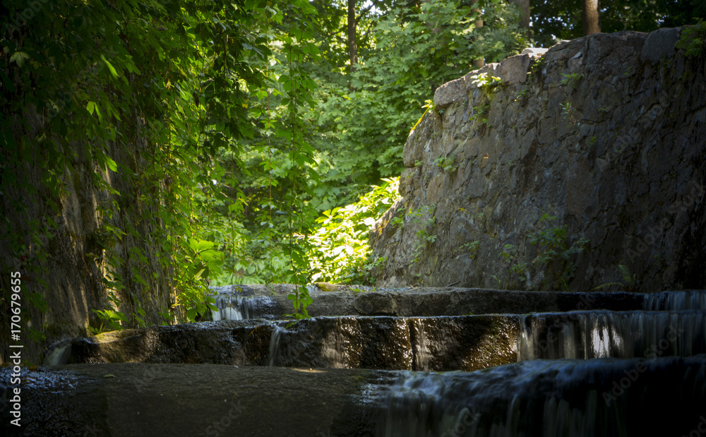 Naklejka premium Decorative waterfall with rapids and overflows in the forest