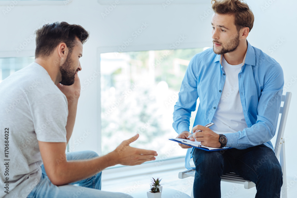 Obraz premium Nice sympathetic doctor listening to his patient