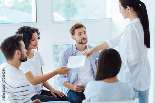 Professional group therapist giving sheets of paper