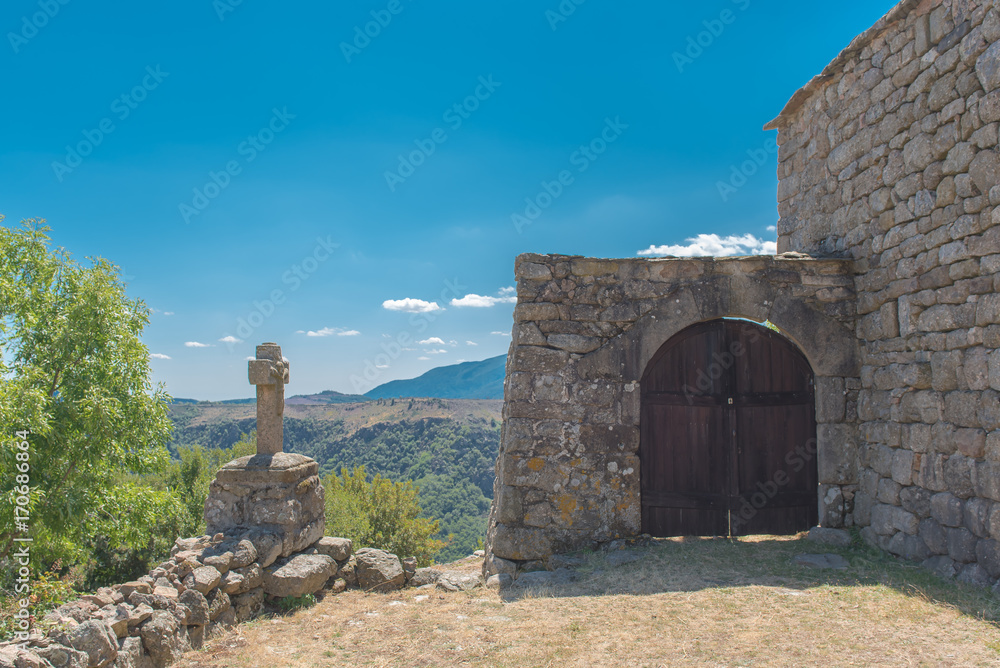 Small village in Lozere, lost in wild landscape, old houses, stone cross at the entry porch, Cevennes in France
