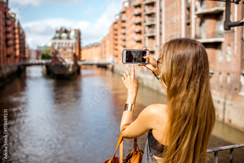 Young woman tourist photographing beautiful view on the Speicherstadt, historic warehouse district in Hamburg, Germany photo